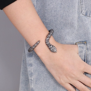 Vintage oxidized silver snake bangle featuring detailed scales on light denim background