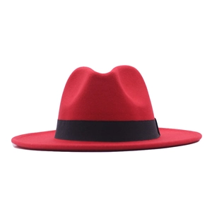 Macro detail of red wool felt fedora featuring a classic wide brim and black band