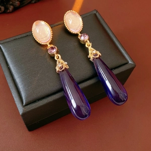 Détail macro de boucles d'oreilles vintage dorées avec cristaux violets et opale résine
