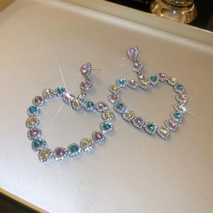 Détail de boucles d'oreilles cœur avec cristaux multicolores et monture argentée
