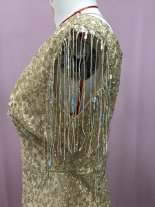 Dettaglio dell'abito con paillettes color oro champagne e nappe luccicanti sulla spalla