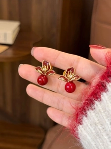 Vue détaillée de boucles d'oreilles fleurs rouges avec bordure dorée et perle