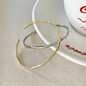 Close-up of gold and silver irregular hammered texture open bangles on a ceramic plate