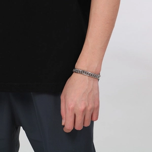 Gros plan détaillé d'un bracelet gourmette en acier inoxydable argenté sur un mannequin