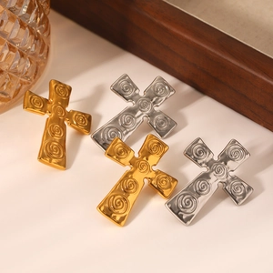 Detail of vintage gold and silver cross earrings with spiral texture and relief patterns