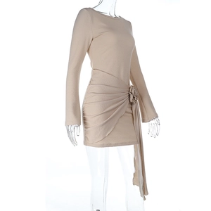 Detail of the light beige long-sleeve dress with a large 3D floral accent and draped folds