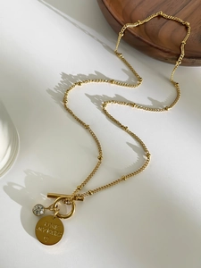 Detail of gold heart pendant necklace with Love My Kids engraving and crystal on wood bowl