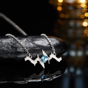 Macro shot of S925 silver heartbeat necklace with blue topaz stone on black stone base