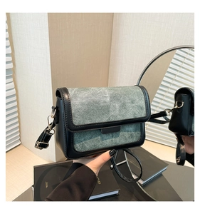 Detail of vintage green denim crossbody bag with black leather trim and gold metal hooks