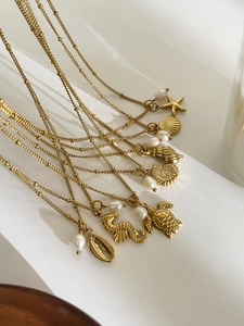 Detailed close-up of gold ocean theme necklaces with sea turtle, seahorse and pearl charms