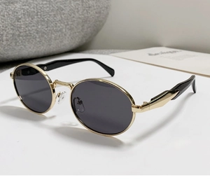 Detail einer ovalen Vintage-Sonnenbrille mit Goldrahmen und schwarzen Gläsern im Profil