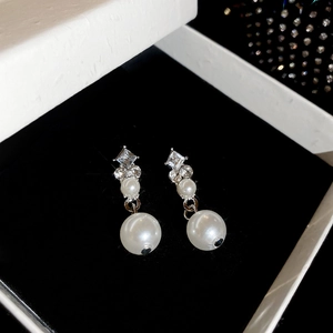 Close-up of diamond-studded pearl earrings on black velvet padding in a luxury gift box