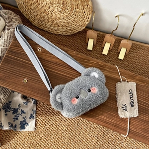 Detail of grey plush koala purse with soft fur and embroidery on a wooden surface