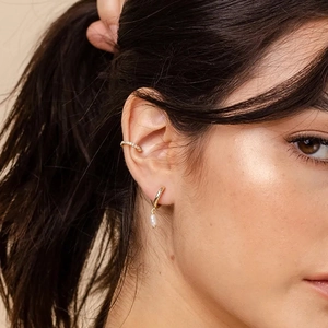 Detail of S925 silver star earring with pearl and cubic zirconia on a model ear