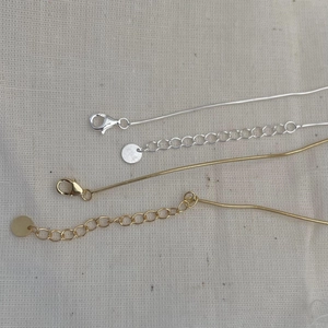 Macro detail of gold and silver S925 snake chain bracelet with lobster clasp and extension