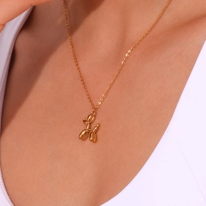 Close-up of golden balloon dog pendant necklace worn by model showing style and scale