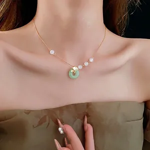 Ginkgo leaf necklace with green donut pendant and white beads on a gold plated chain