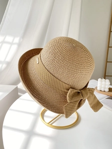 Détail du chapeau de paille tressé avec nœud élégant et pendentif logo doré en métal