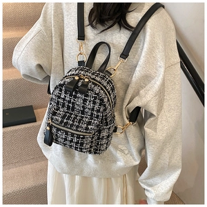 Black and white tweed mini backpack with gold zippers shown on a model's back