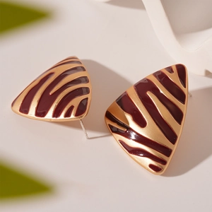 Gros plan détaillé des boucles d'oreilles triangulaires à motif zèbre en émail rouge