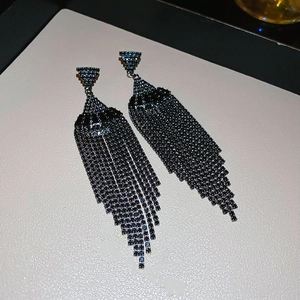 Détail de boucles d'oreilles élégantes à franges et pompons en strass noirs chic