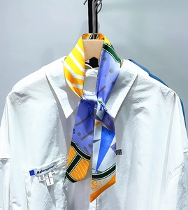 Detailed view of patterned silk scarf draped over a white collared shirt with pocket