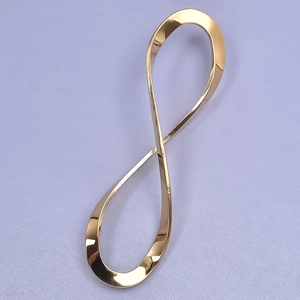 Macro shot of a golden figure-eight infinity pendant on smooth light purple fabric