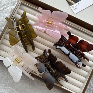 Close-up of five large butterfly hair claws in various matte colors in a jewelry box
