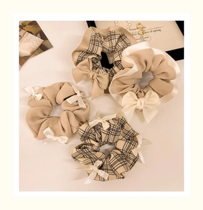 Detailed view of four elegant bow scrunchies in khaki waffle and brown plaid patterns