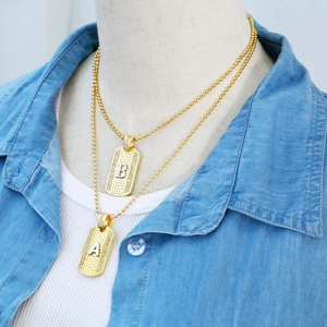 Detail of layered gold ball chain necklaces with embossed A and B letter pendants