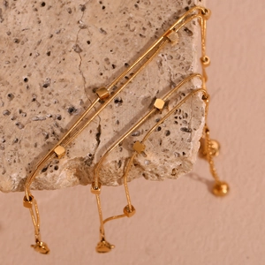 Detailed close-up of a 18K gold-plated double-layer snake chain anklet on a textured stone