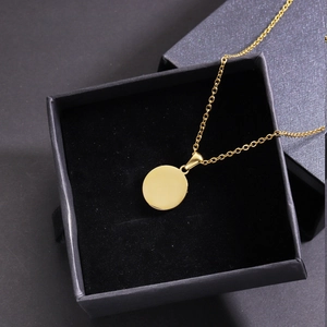 Golden round shell pendant necklace displayed on a black velvet lining inside a gift box