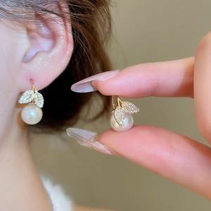 Detail of fishtail leaf pearl earrings with zircon inlay worn on a model's ear