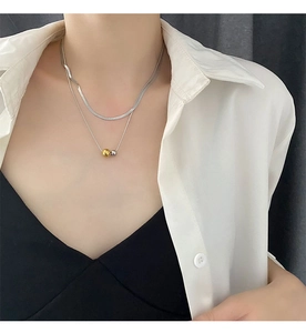 Detail of minimalist double-layered stainless steel necklace with gold and silver beads