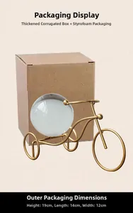 Detailed view of gold metal tricycle ornament with crystal ball and its packaging box