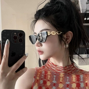 Fashionable black cat eye sunglasses with bold gold chain temples worn by a model