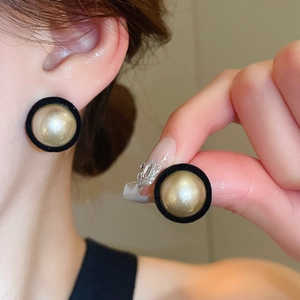 Detail view of a vintage round earring with champagne pearl and black velvet texture