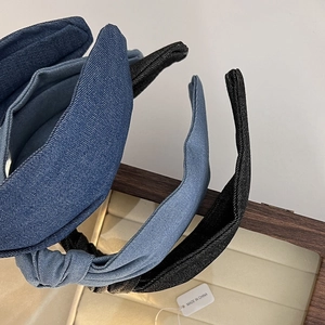 Close-up of three knotted denim headbands in dark blue, light blue, and black colors