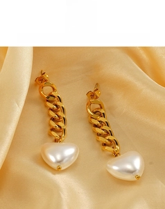 Detail of 18K gold chain earrings featuring white heart pearls on champagne silk fabric