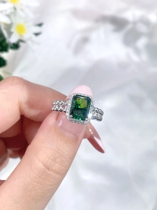 Detailed close-up of S925 silver ring featuring emerald cut green gemstone and pavé diamonds