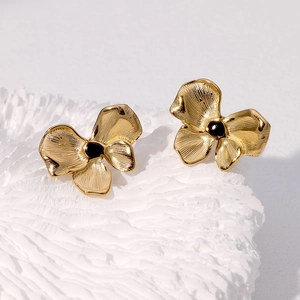 Gros plan sur des boucles d'oreilles nœuds dorés avec centre noir sur fond blanc