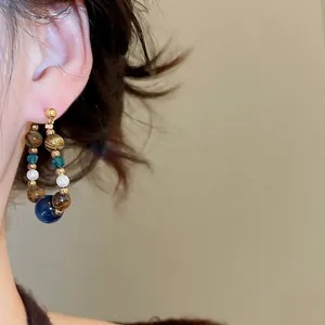 Retro beaded hoop earrings with tiger eye, pearls, and blue beads worn on model
