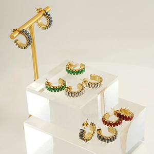 Detail of gold C-shaped earrings with colorful step-cut zircons on a display stand