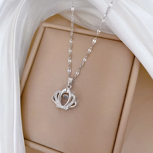 Macro shot of silver crown pendant necklace with sparkling zirconia on silk background
