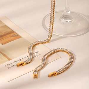 Detail of a gold bracelet featuring rectangular clear zircons on a luxury background