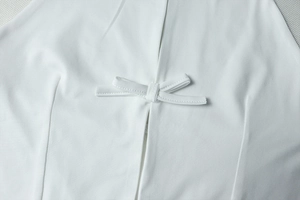 Détail d'un ensemble blanc deux pièces avec nœud en tissu et fente sur jupe midi