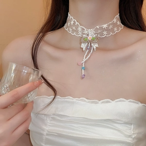 Detail of white lace choker necklace featuring ribbon bow with colorful beads tassels