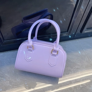 Fashionable light purple jelly Boston handbag with golden hardware on reflective floor