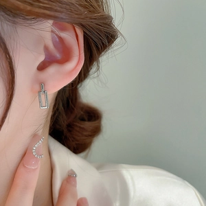 Close-up of minimalist silver geometric rectangular drop earrings worn by a model