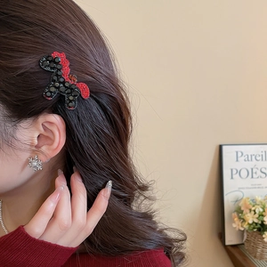Close-up of a poodle-shaped hair clip with red and black rhinestones on a model